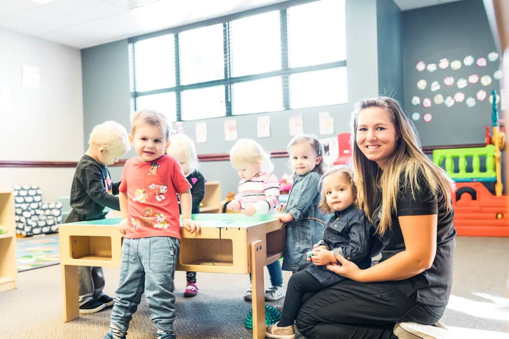 A preschool teacher sitting with her students
